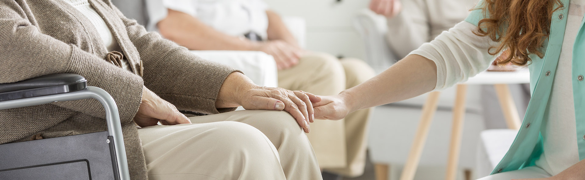 Close-up of young nurse holding her older patient's hand