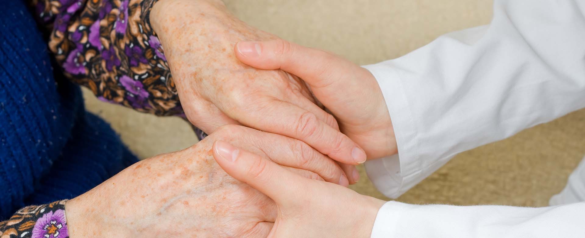 The doctor holding an elderly woman's hand.